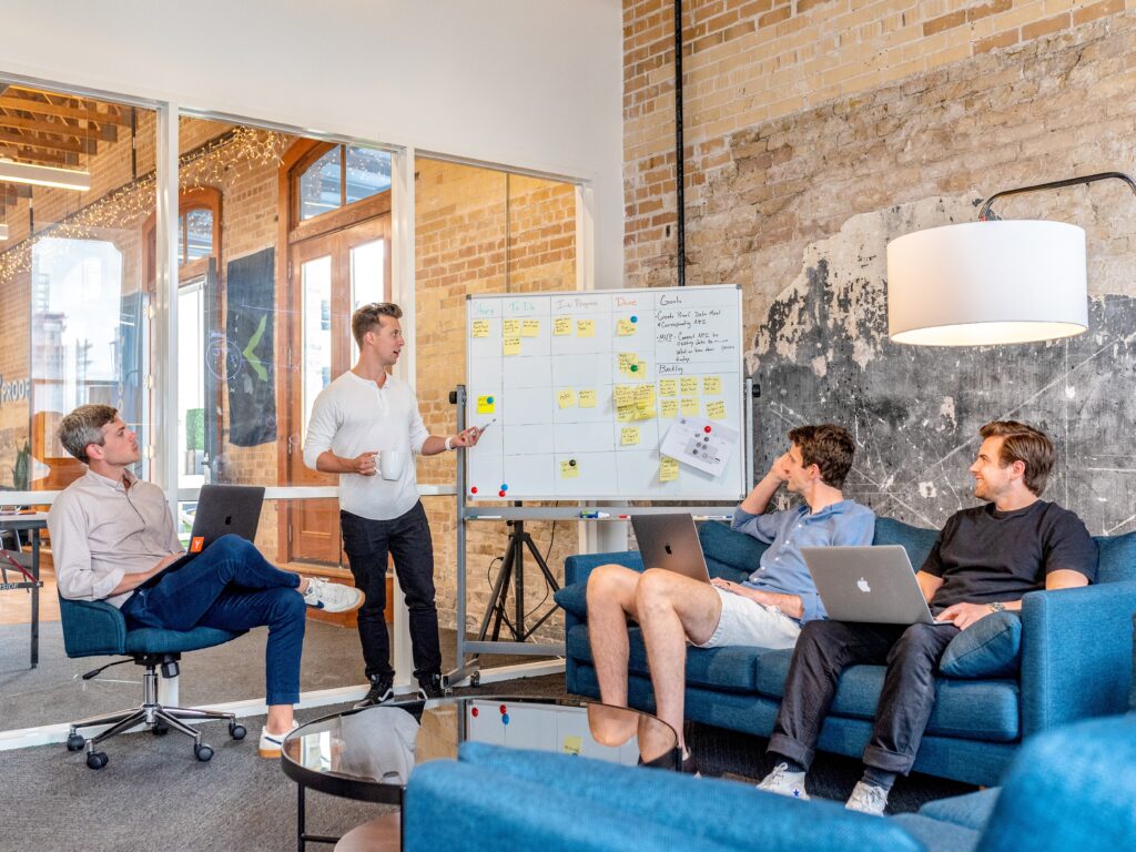 men discussing sitting with laptops whiteboard post its