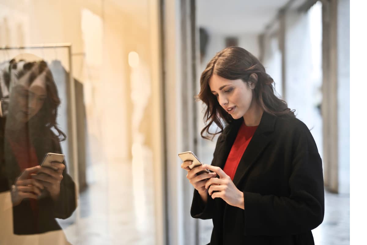 A woman smiling while reading an email on her phone.