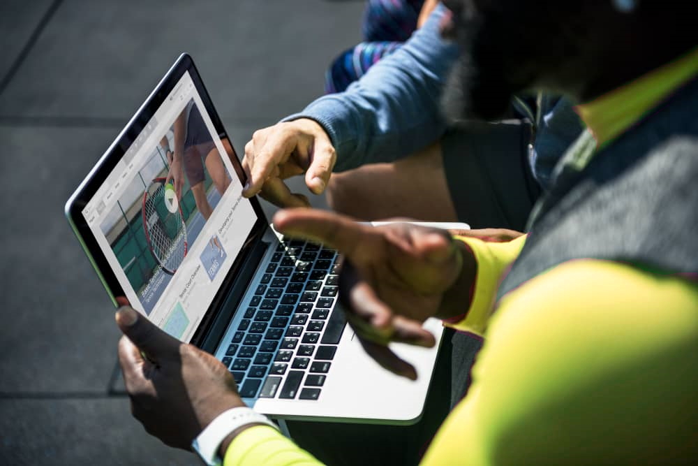 People looking at a tennis video thumbnail on a laptop