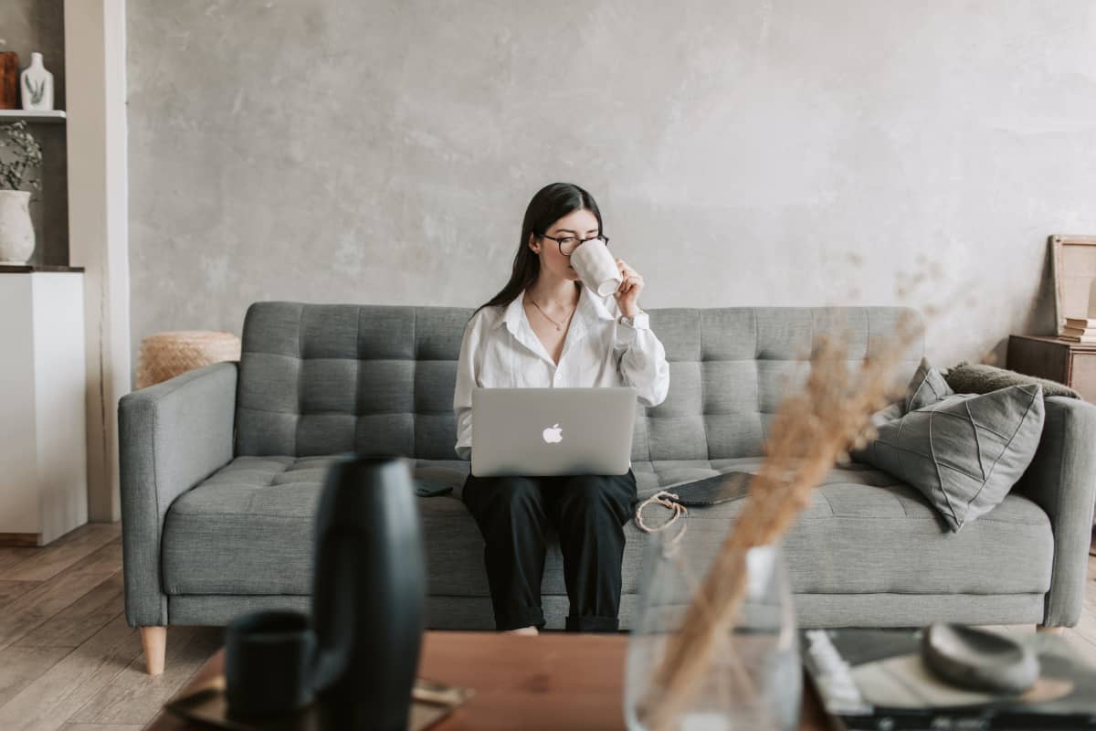 A woman working behind a computer, drinking coffee