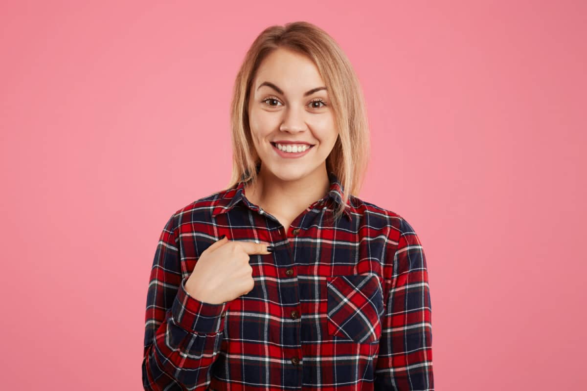 Smiling girl indicates herself with finger