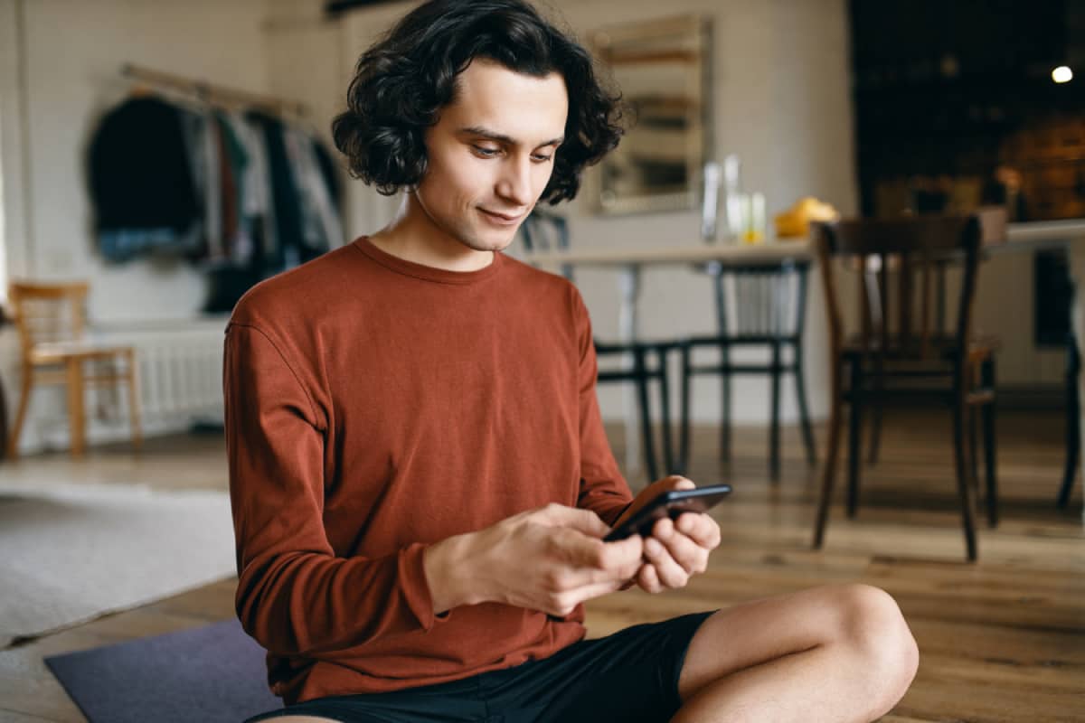 Young person smiling and looking at their phone