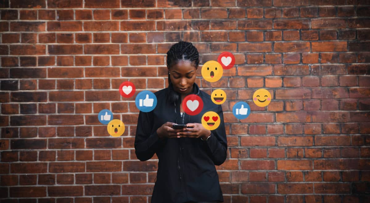 Young woman looking at their phone, surrounded by emojis