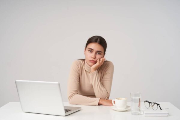Sad and tired email marketer girl behind laptop