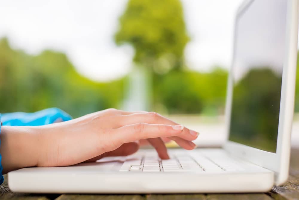 Woman working outdoors with a white laptop