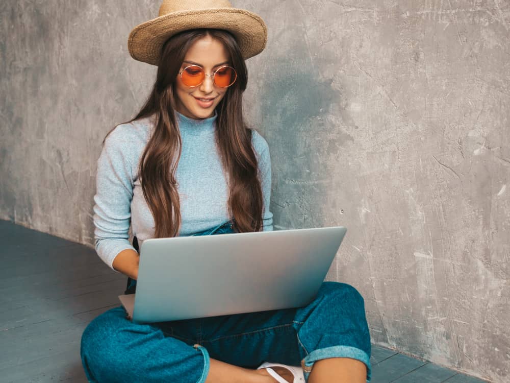 Young freelancer with sunglasses writing on her laptop