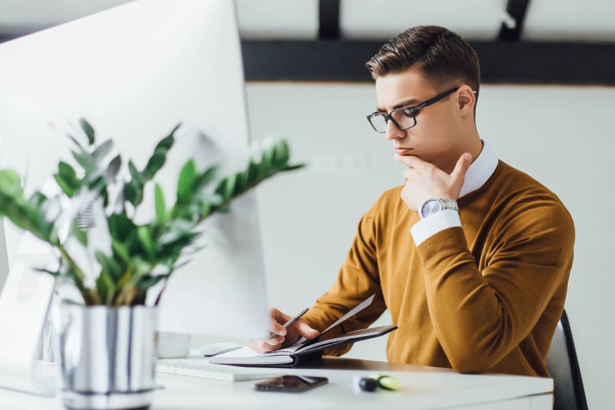 Email marketer thinking and writing down points in his notebook