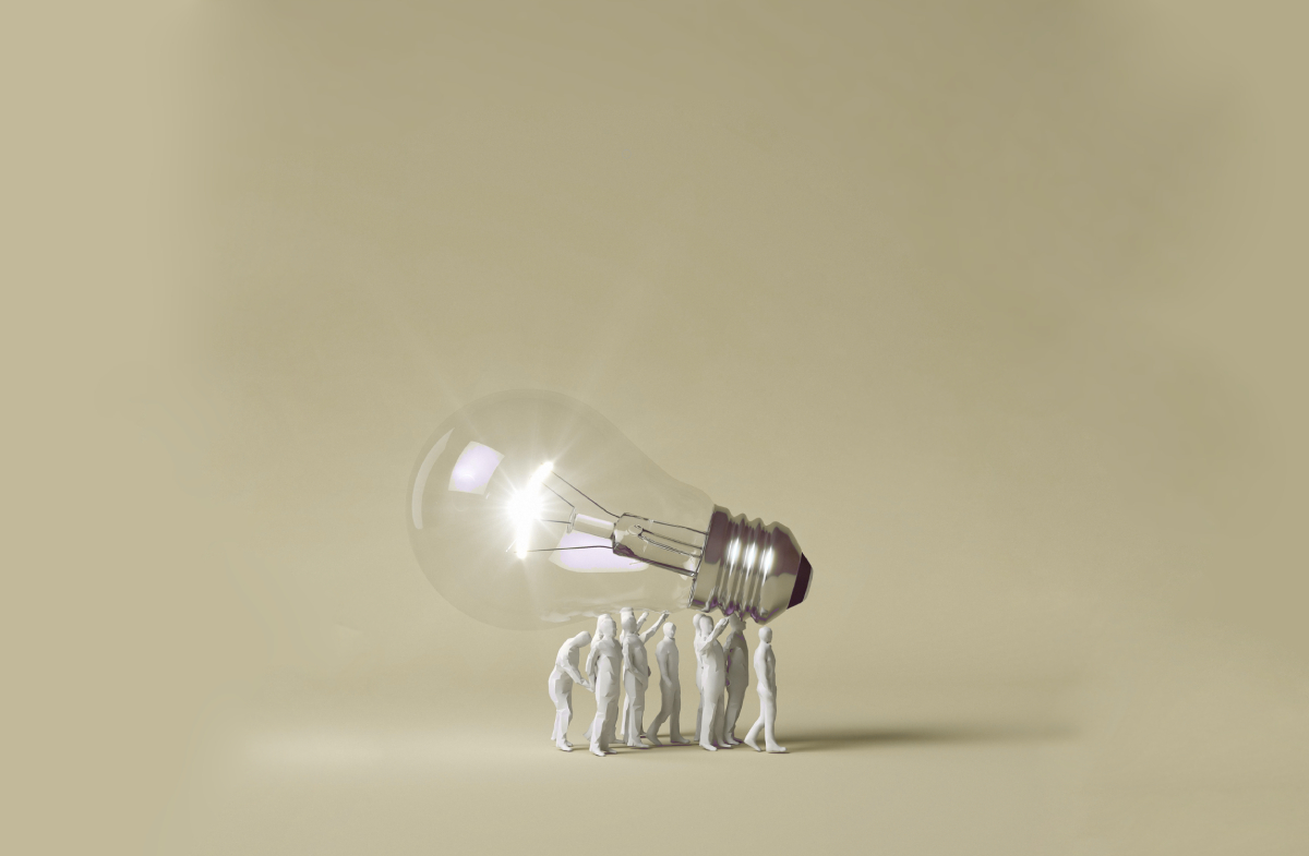 Human figurines carrying a lit lightbulb symbolizing teamwork