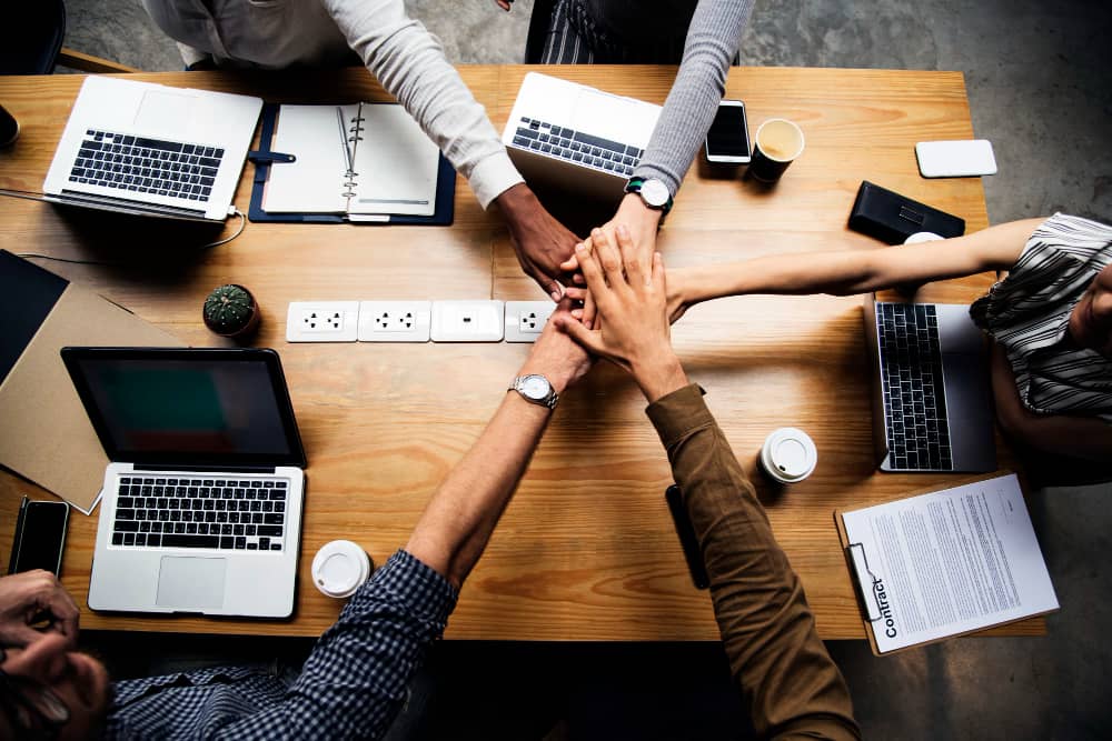 Team of business people stacking hands symbolizing teamwork