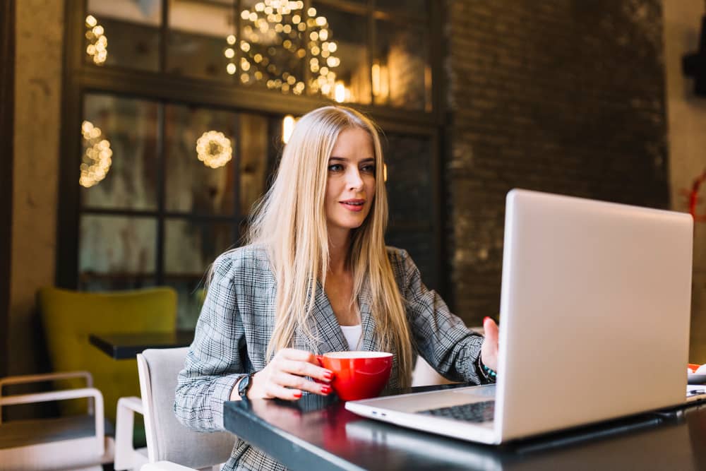 Stylish email marketer with laptop in a coffee shop