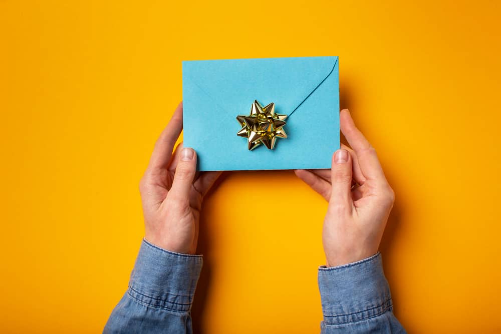 Person giving out an envelope symbolizing a gift given out via email