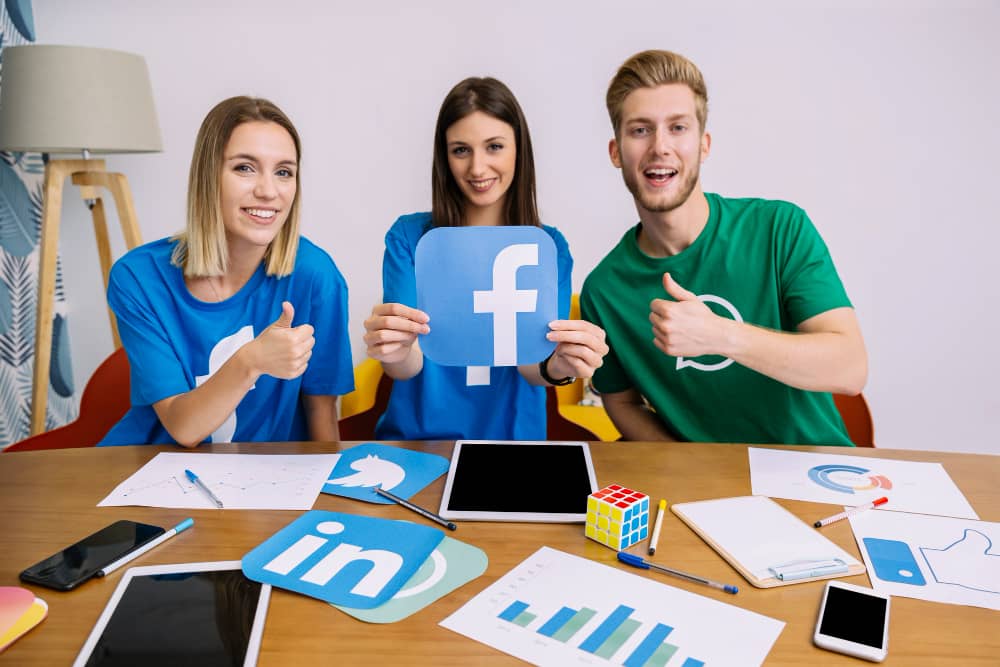 Marketing team holding a Facebook logo showing thumbs up sign