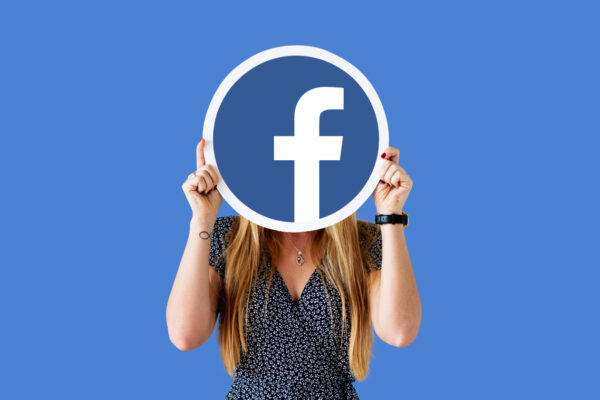 Woman showing Facebook icon - growing email list through Facebook
