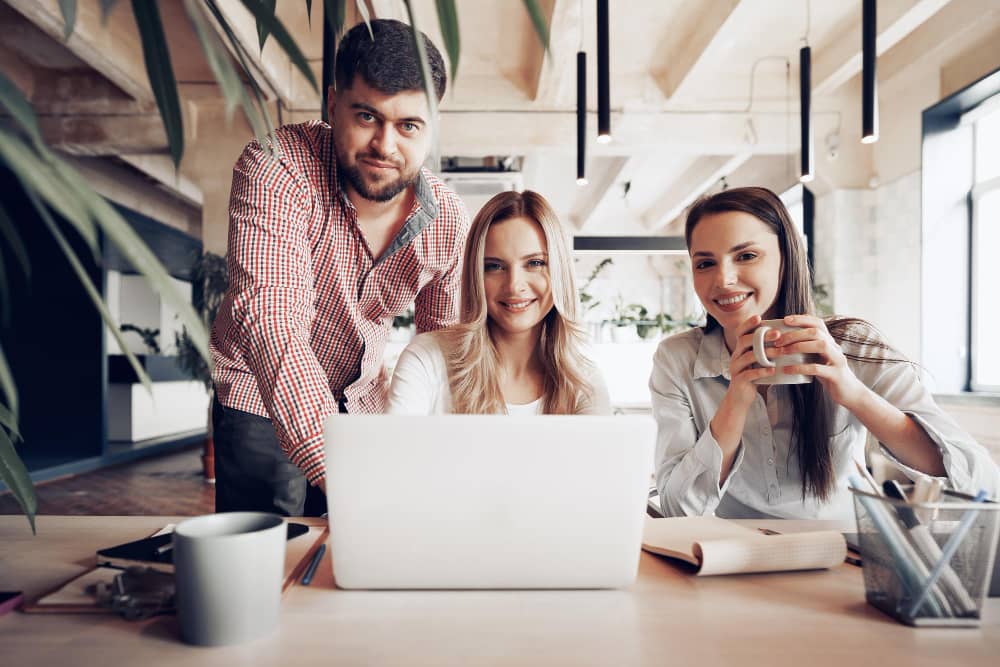 Business partners behind computer screen looking at the viewer