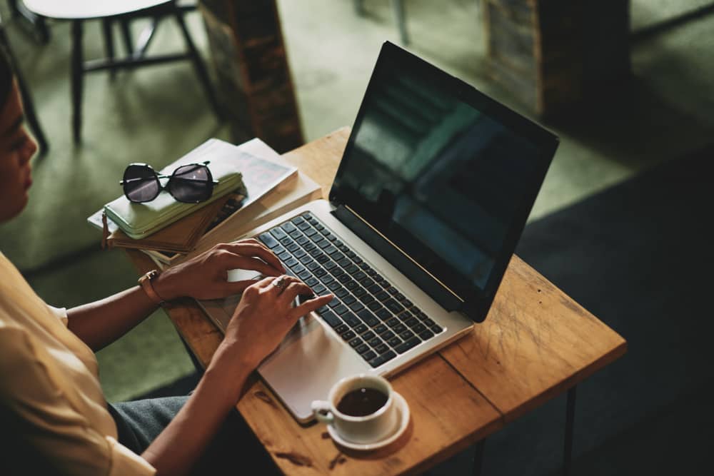 Email marketer sitting in cafe working on laptop