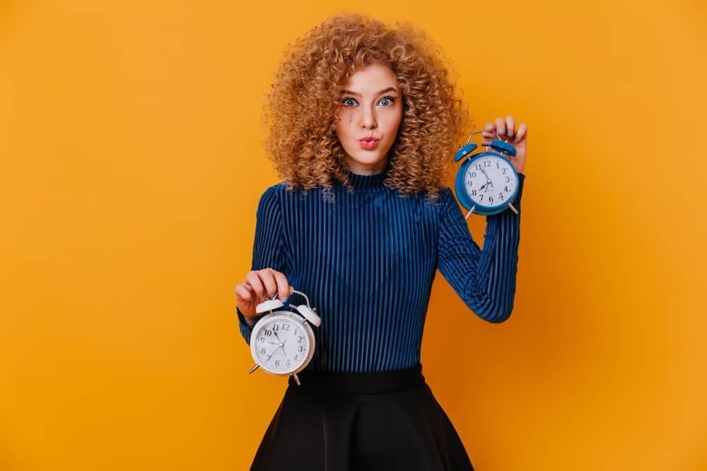 Woman posing with alarm clocks symbolizing timing in email communication