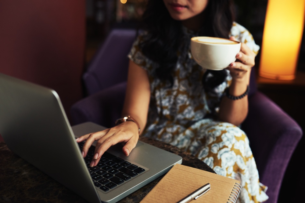 Person with a coffee cup behind a computer, reading a blog article