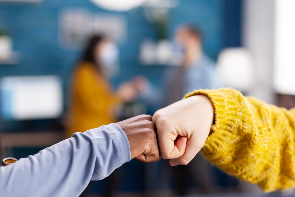 Two people bumping fists, symbolizing teamwork on link exchange to grow your mailing list