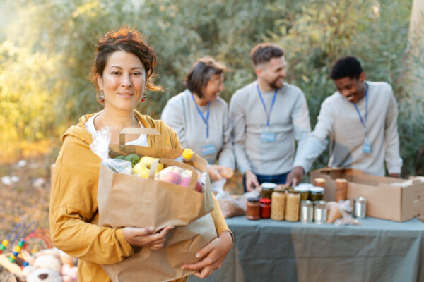 A picture of a group of people doing charity work, a woman with a bag of groceries in the foreground to symbolize nonprofit email marketing