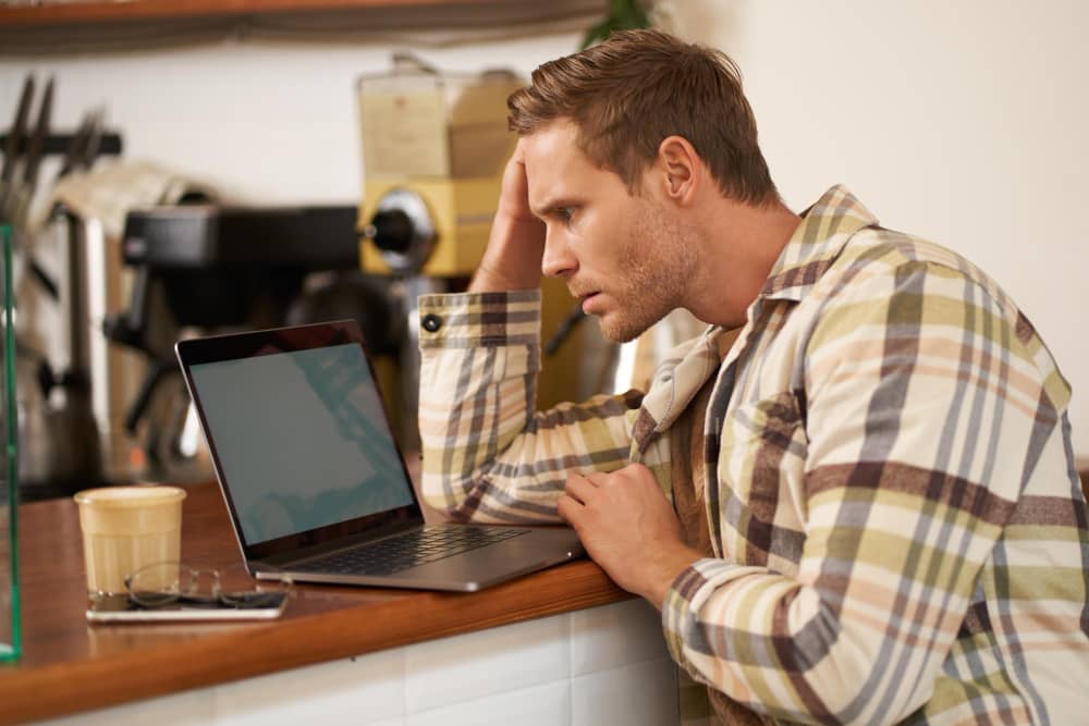 A man looking at his computer, anxiously feeling FOMO