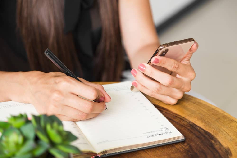 A person reading an event registration email and writing down the date in their calendar