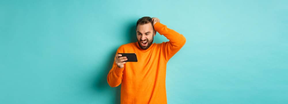 A man looking at his mobile phone with a baffled expression