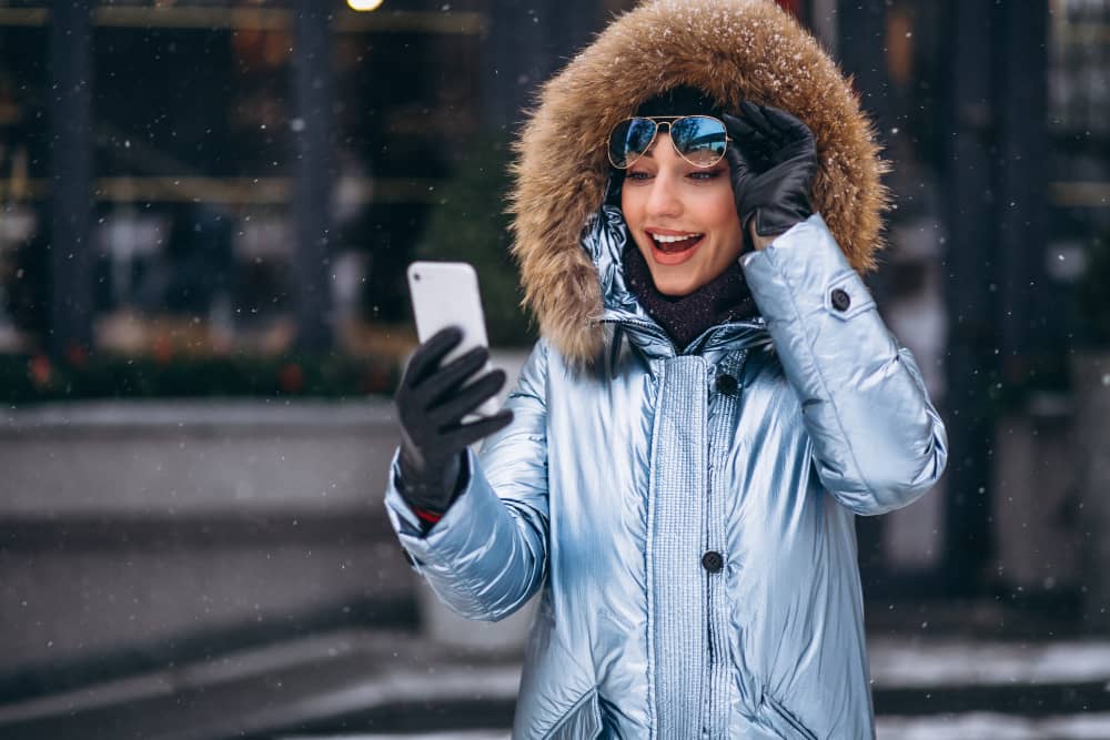 A woman looking at her phone in a cold climate, symbolizing geotargeting in email marketing