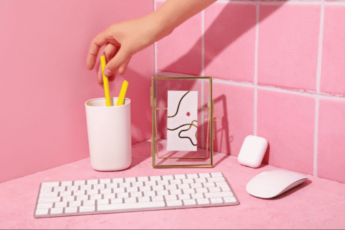 A person grabbing a pen from behind a keyboard