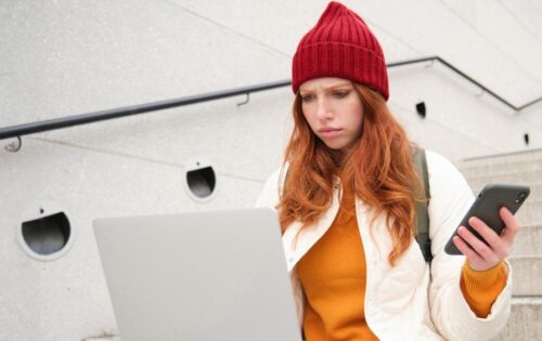 Woman sitting on a staircase and looking at her laptob, being annoyed at spam email