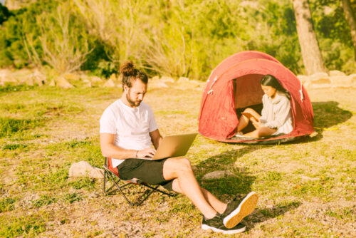 Couple resting in camping and working remotely, symbolizing summer email marketing