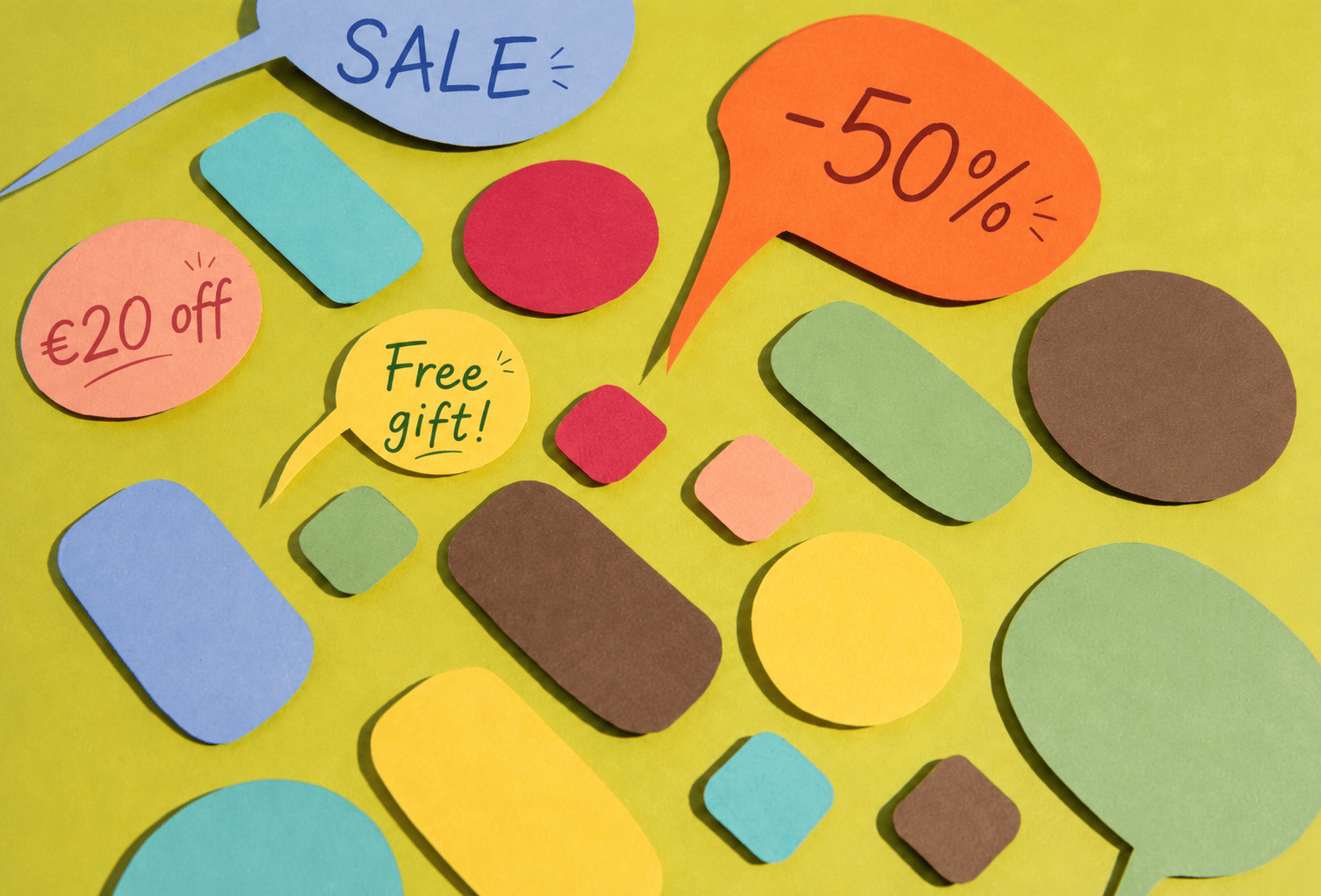 Colorful paper speech bubbles on a bright green background with handwritten promotional messages, including SALE, -50%, €20 off, and Free gift!, representing playful email marketing promotions.