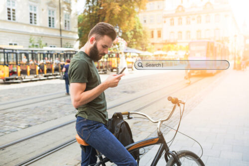 Man on a bicycle using the search bar in his mobile, symbolizing browsing history in email marketing
