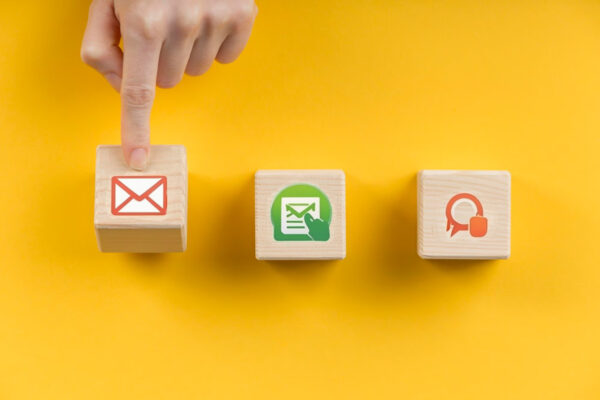 Three wooden blocks with signs, symbolizing email, SMS, or push notifications