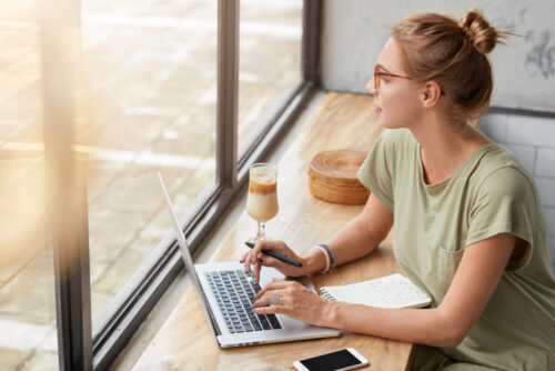 A copywriter working behind her laptop and looking out of a window