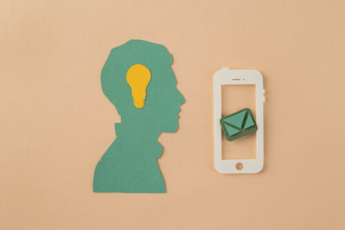A person with a glowing lightbulb above their head and an email envelope displayed on a smartphone, symbolizing email marketing ideas